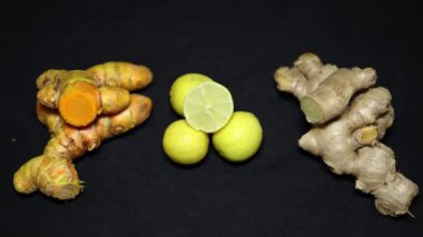 Siyah arka planda taze çiğ zerdeçal, limon ve zencefil.