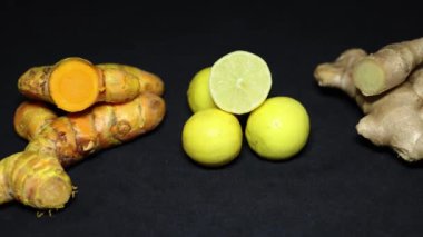 Siyah arka planda taze çiğ zerdeçal, limon ve zencefil.