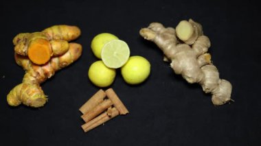 Siyah arka planda taze çiğ zerdeçal, limon, zencefil ve tarçın çubuğu.