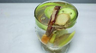 Stüdyo ışığında taze pancar kökü dilimleri ve diğer çiğ sebzelerle bir bardak su.