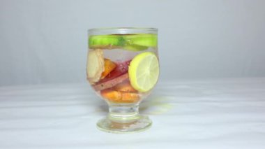 Stüdyo ışığında bir bardak taze zerdeçal, limon, salatalık, pancar ve zencefil.