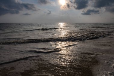 Deniz ufku parlak gün doğumuyla kumlu sahilden mavi gökyüzü ve sabah dalgaları