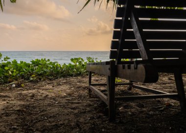 wood beach chair sitting with sea horizon sunrise view from unique perspective at morning image is taken at Kala Pathar Beach havelock Andaman and Nicobar Islands. clipart