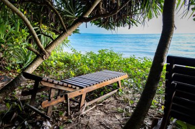 wood beach chair sitting with sea horizon sunrise view from unique perspective at morning image is taken at Kala Pathar Beach havelock Andaman and Nicobar Islands. clipart