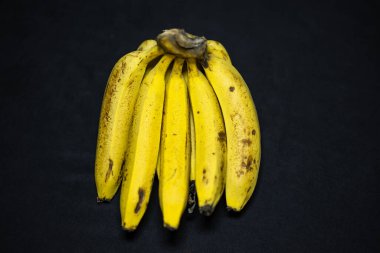 Stüdyo ışığı altında taze, sarı muz, siyah arka planda.