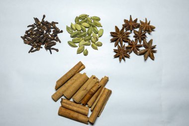 Taze çiğ karanfil, kakule, yıldız anason ve tarçınlı çubuk beyaz arka planda stüdyo ışığı.
