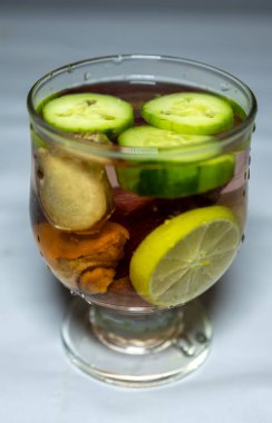 glass of water with Slices of Fresh Cucumber and other raw vegetables in studio light clipart