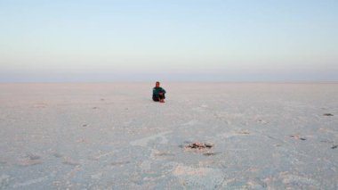Genç adam mavi gökyüzü ile beyaz çölde oturuyor. Video, dhordo kutch beyaz rann gujrat Hindistan 'da çekiliyor..