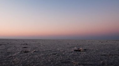 Uzak beyaz tuzlu çölde, parlak turuncu gökyüzü ve alçak açılı videolarla eğlenen genç çift, Dhordo Kutch White Rann Gujrat Hindistan 'da çekiliyor..