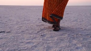 Genç bir kız sabahın köründe uzak beyaz tuzlu çölde yürüyor. Üst açıdan çekilen video Dhordo Kutch White Rann Gujrat Hindistan 'da çekiliyor..