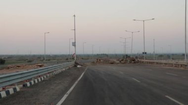 Asfalt yol, akşamları gökyüzü güneşli, atık derbilerle tıkanmış.