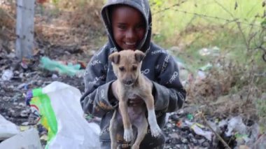 Masum fakir çöp toplayan sevimli gülüşü ve köpeği olan bir çocuk.