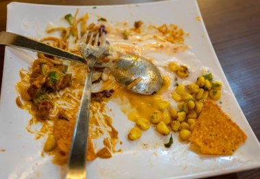 Çapraz kaşık ve çatal boş tabak üzerinde bitirilmiş yemeği simgeliyor.