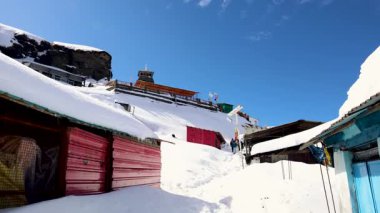 Arkaplanda açık mavi gökyüzü olan karla kaplı kutsal Hindu tapınağı.