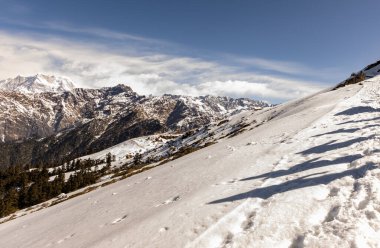 Yürüyüş grubunun gölgesi sabah taze beyaz kar üzerinde yürürken Chandrashila trek tungnath chopta uttarakhand Hindistan 'da çekilir..