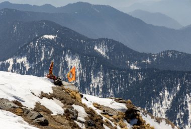 Bulutlu mavi gökyüzü altında kutsal bayrağı olan kar örtüsü dağ manzarası Chandrashila yürüyüşü tungnath chopta uttarakhand Hindistan 'da çekilmiştir..