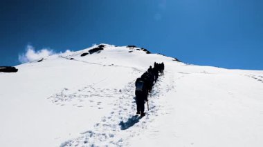 Gün ışığında açık mavi gökyüzü altında karlı zirveye tırmanan yürüyüş ekibi Chopta Tungnath Himalayas dağında çekildi. Chandrashila dağında..