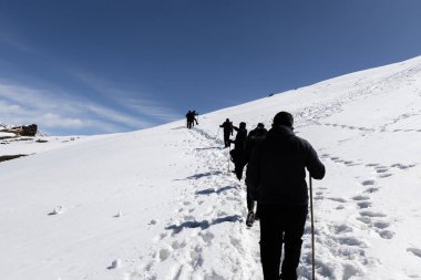 Gün ışığında açık mavi gökyüzü altında karlı zirveye tırmanan yürüyüş ekibi Chopta Tungnath Himalayas dağında çekildi. Chandrashila dağında..
