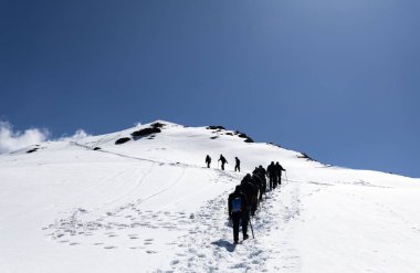 Gün ışığında açık mavi gökyüzü altında karlı zirveye tırmanan yürüyüş ekibi Chopta Tungnath Himalayas dağında çekildi. Chandrashila dağında..