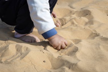 Masum bir çocuk düz bir perspektiften çöl kumunu elle keşfediyor.