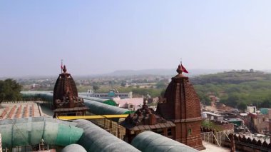 Kutsal bayrak sallayan antik Hindu tapınağı ve buğulu dağlar sabah çekilen video Osiyan Sacchiyay Mata Tapınağı, jodhpur, Rajasthan, Hindistan 'da çekilmiştir..