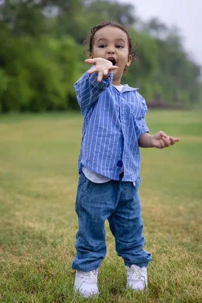 tapılası Hintli çocuk sabahları dışarıda sevimli bir ifadeyle el hareketi yapıyor.