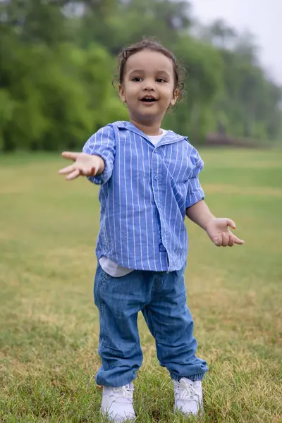 tapılası Hintli çocuk sabahları dışarıda sevimli bir ifadeyle el hareketi yapıyor.
