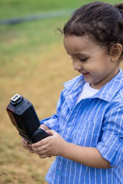 Hindistanlı çocuk, sabah dışarıda sevimli yüz ifadesi olan bir nesneyle oynuyor.