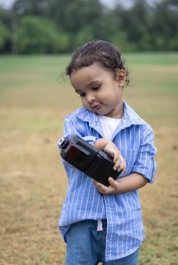 Hindistanlı çocuk, sabah dışarıda sevimli yüz ifadesi olan bir nesneyle oynuyor.