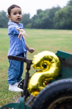 Hindistanlı çocuk, sabah dışarıda sevimli yüz ifadesi olan bir nesneyle oynuyor.