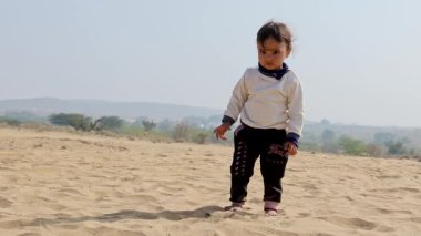 Gündüz vakti çölde kumla oynayan masum bir çocuk Rajasthan, Hindistan 'da çekiliyor..