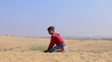 Çölde sarı kumla oynayan çocuk Hindistan, Rajasthan 'da çekiliyor..