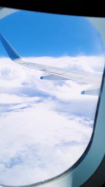 uçuş penceresi bulutların üstündeki parlak mavi gökyüzü ve gün içindeki uçak kanadı