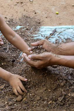 Yetişkin ve çocuk kaynaşırken temiz bahçe toprağı ve açık havada toprak temasını koru