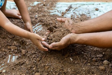 Yetişkin ve çocuk kaynaşırken temiz bahçe toprağı ve açık havada toprak temasını koru