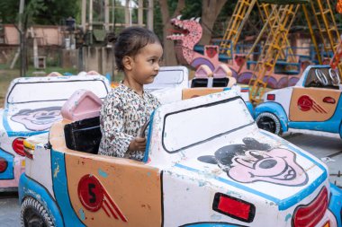 Çocuk arabasıyla eğlenen mutlu çocuk gün ortasında festival alanında sallanıyor.