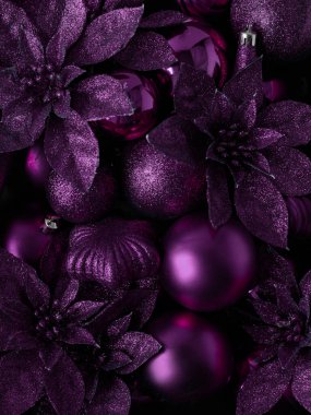 Mor Noel baloları ve çiçekler. Yazıtın arka planı. Noel arkaplanı. Yeni yıl konsepti. Yukarıdan bak. Mutlu Noeller ve mesaj için boşluklu yeni yıl kartı. Seçici odaklanma.