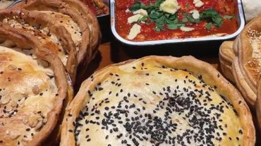 Peynir ve otlarla domates tabanlı bir tabağın yanında tohumlu altın esmer turtalar. Fırın, ev yapımı yemekler ve mutfak temaları için mükemmel..