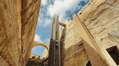 Bu modern, hızlı ve rahat cam asansör Valletta, Malta 'nın tarihi kireçtaşı duvarları boyunca seyahat ederek çarpıcı manzaralar sunuyor. Turistler arasında popüler olan liman, limanı yukarıdaki şehre bağlıyor. Geniş açı çekimi.
