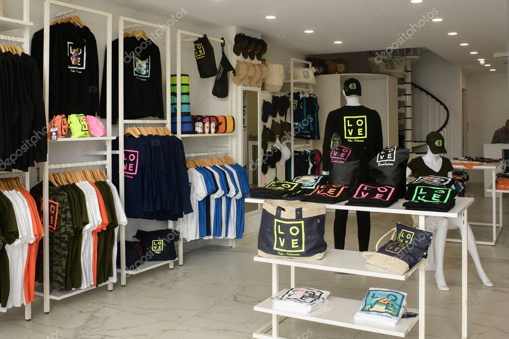 Gzira, Malta- 04.05.2025: Modern clothing store interior with colorful LOVE print streetwear, including t-shirts, hoodies, caps, and bags, neatly displayed on racks and tables.