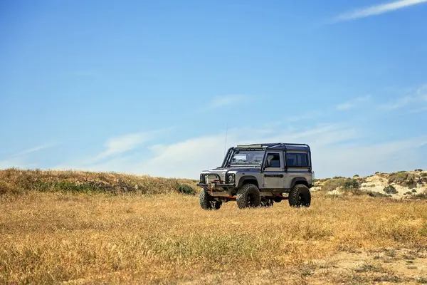Güçlü off-road aracı mavi gökyüzünün altında kuru çimlere park edilmiş. Manzaralı vahşi doğa, özgürlük ve macera. Seyahat, keşif ve açık hava yaşam tarzı temaları için ideal kavram.