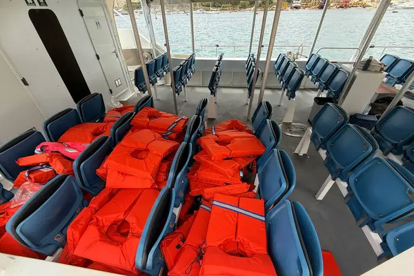 Mavi koltuklara düzgün yerleştirilmiş parlak kırmızı can yelekleriyle feribot güvertesi manzarası denizi geçmeden önce güvenlik hazırlıklarını vurguluyor..