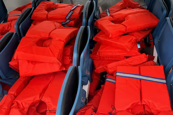 Yeni parlak kırmızı can yeleklerini mavi koltuklara düzgünce yerleştirin. Deniz yolculuğuna çıkmadan önce bir deniz gemisinde güvenlik kavramı.
