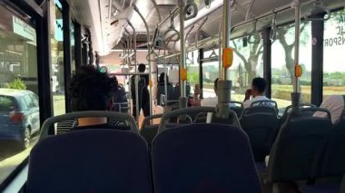 Zabbar, Malta - 06.01.2025: Güneşli bir günde hareket halindeki otobüste bulunan yolcular, düz yol ve gerçekçi kentsel ulaşım deneyimi nedeniyle hafif bir kamera sallaması ile iç mekan görüntüsü. Arka koltuklardan bak.