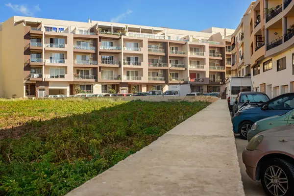 Balkonları, küçük sebze bahçeleri olan modern bir apartman dairesi ve bir yerleşim bölgesine park edilmiş arabalar. Yoğun Akdeniz şehirlerinde günlük yaşam ve arazi kullanımını yansıtır.