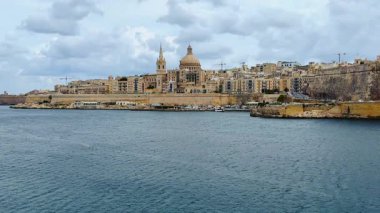Denizden Valletta 'nın tarihi manzarası, Malta. Eski binalar, kilise kubbeleri, liman, botlar, dramatik bulutlu gökyüzü, Akdeniz kıyısı. Seyahat, mimari, Avrupa.