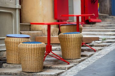 Avrupa 'nın dar yokuşlu bir sokağının taş basamaklarında mavi yastıklı ve kırmızı masalı hasır tabureler. Turistlerin dinlenmesi ve açık hava kafesinin cazibesinin tadını çıkarması için mükemmel bir yer..