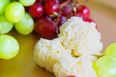 Belleray 'dan, Tte de Moine' den, yeşil ve kırmızı üzümlerle servis edilen peynir çiçeklerini yakından çek..