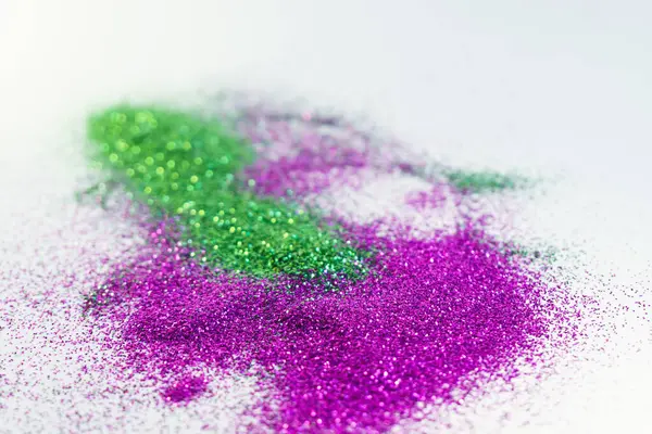 Pink and green glitter spilled on a white background. Glitter banned from sale in Europe concept.