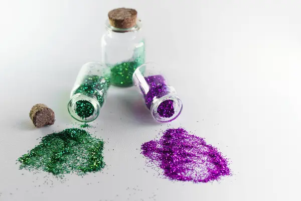 Glitter bottles spilled on a white background with copy space. Concept of glitter sales ban in Europe.